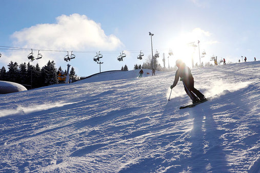 Skifahrer auf der Piste mit Fallbachlift im Hintergrund 